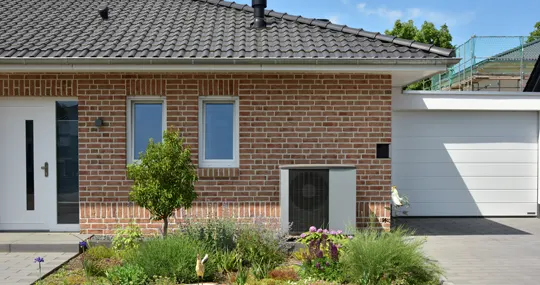 Moderne Wärmepumpe vor einem Bestandsgebäude